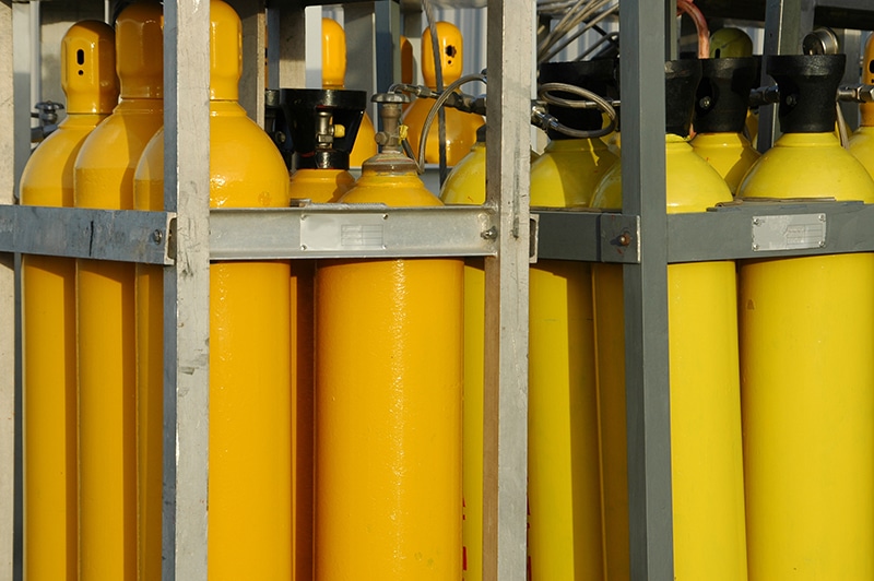 A collection of yellow gas tanks in cages