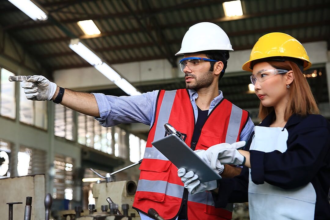 Supervisor and engineer wearing safety uniform and equipment discussion at work shop or factory